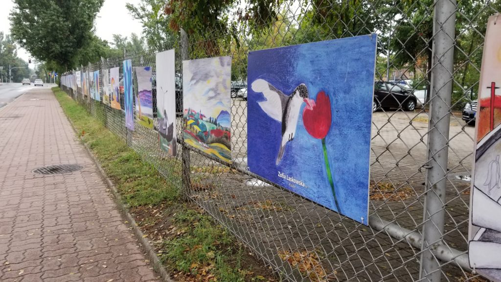 Student paintings hung on a fence