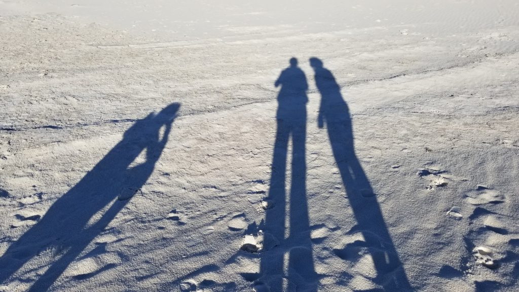 Shadows of three women against the white sands.