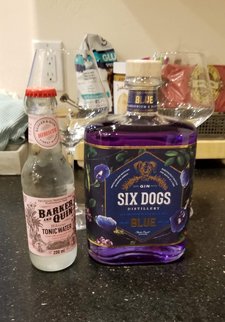 Bottle of tonic water next to bottle of gin.